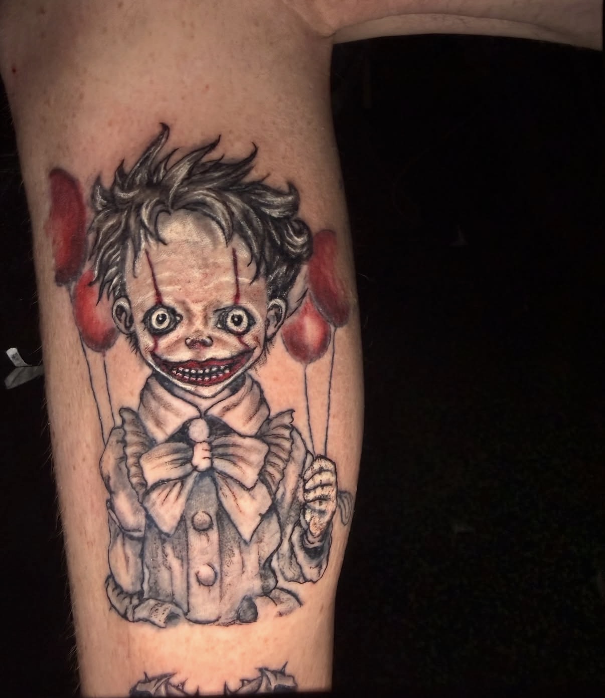 Horror clown marionette tattoo with red balloons on a lower leg